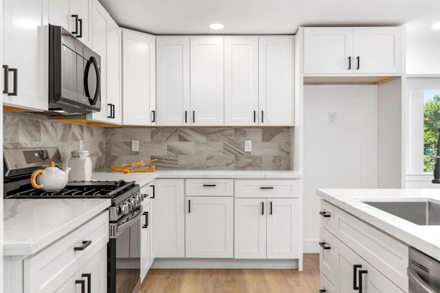 kitchen with light stone counters, white cabinetry, and appliances with stainless steel finishes