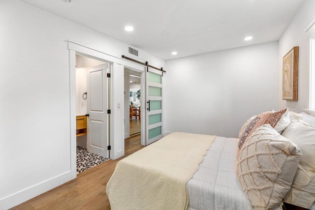 bedroom featuring light wood-type flooring and a barn door