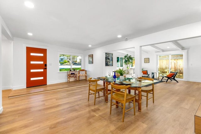 dining area featuring light hardwood / wood-style floors and vaulted ceiling with beams