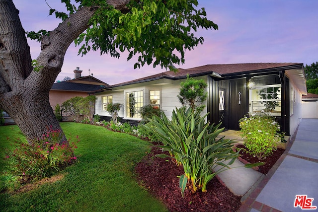 property exterior at dusk with a lawn