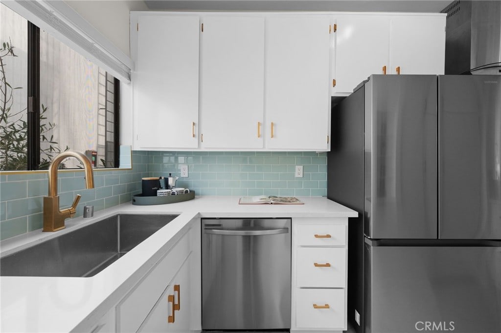 kitchen with tasteful backsplash, white cabinetry, sink, and appliances with stainless steel finishes