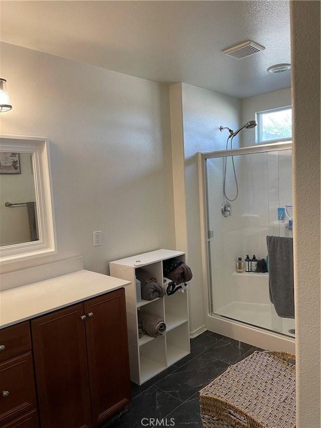 bathroom featuring vanity, a shower with shower door, and a textured ceiling