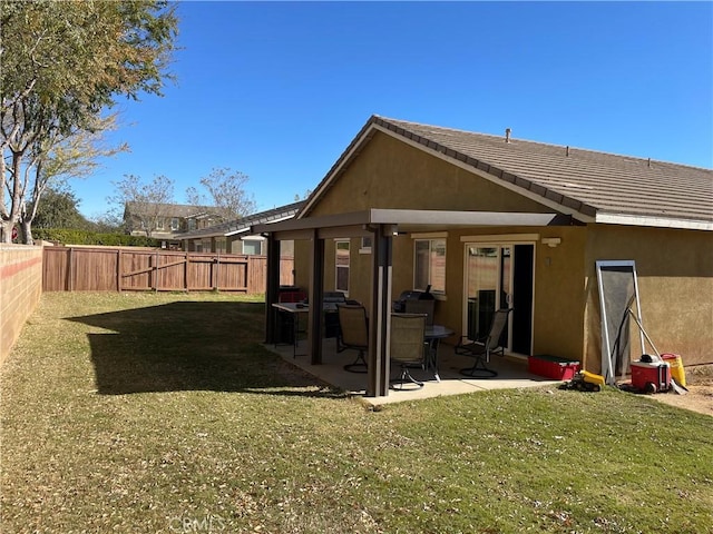 back of house featuring a lawn and a patio area