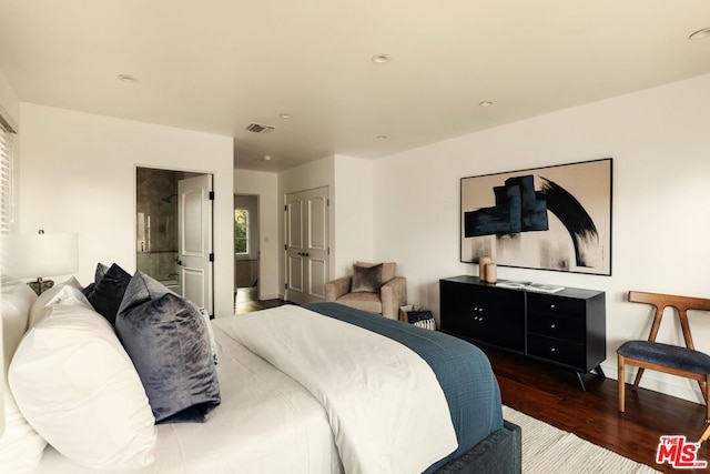 bedroom with ensuite bathroom and dark hardwood / wood-style flooring