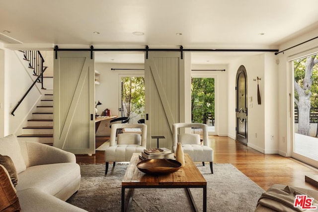 living room featuring a barn door, light hardwood / wood-style flooring, and plenty of natural light