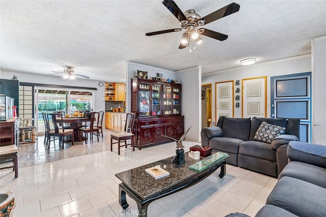 tiled living room featuring ceiling fan, a textured ceiling, and ornamental molding