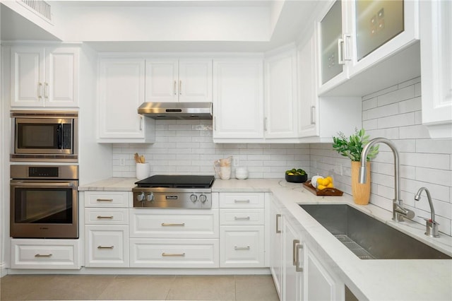 kitchen featuring light stone countertops, sink, stainless steel appliances, backsplash, and white cabinets