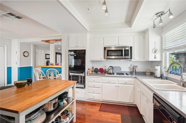 kitchen with dark hardwood / wood-style flooring, white cabinetry, sink, and black appliances