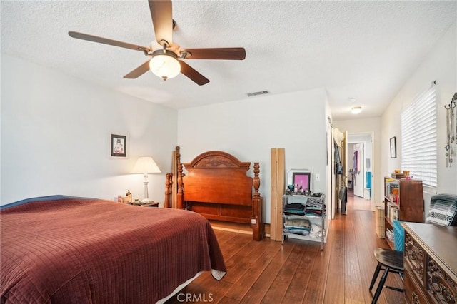 bedroom with a textured ceiling, dark hardwood / wood-style floors, and ceiling fan