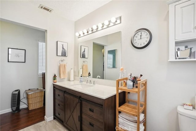 bathroom featuring vanity, wood-type flooring, a textured ceiling, and toilet