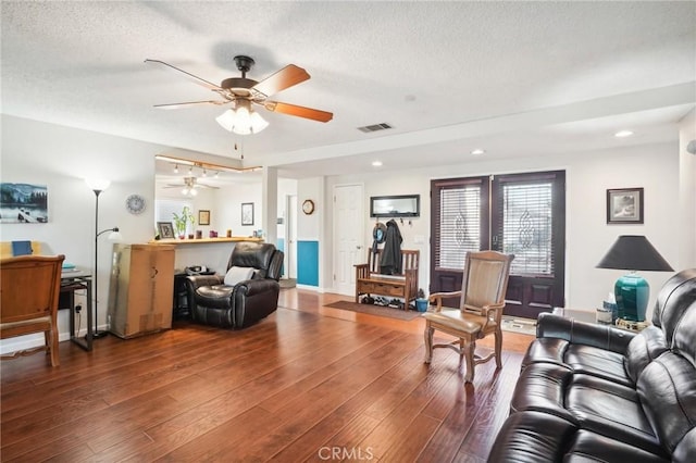 living room with ceiling fan, wood-type flooring, and a textured ceiling