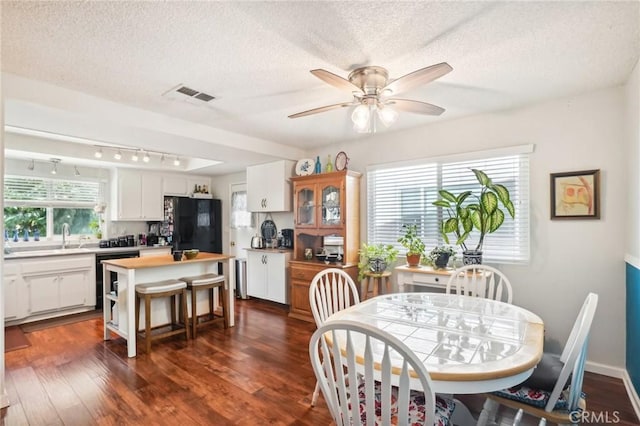 dining space with a textured ceiling, dark hardwood / wood-style flooring, and plenty of natural light