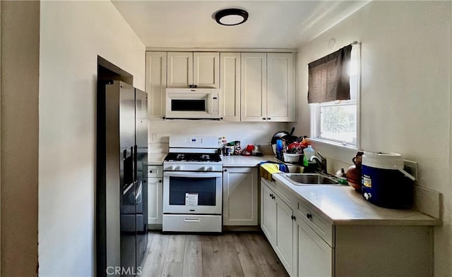 kitchen featuring white cabinets, stainless steel appliances, light hardwood / wood-style flooring, and sink