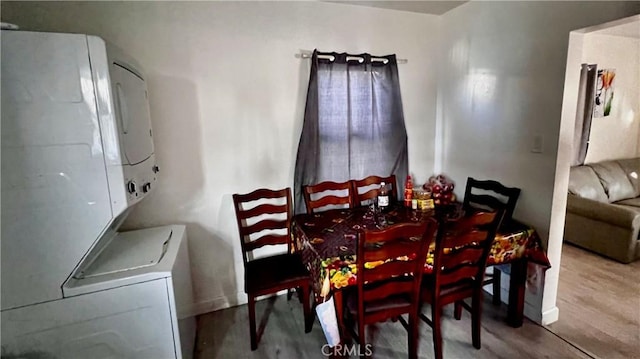 dining area featuring stacked washing maching and dryer and wood-type flooring