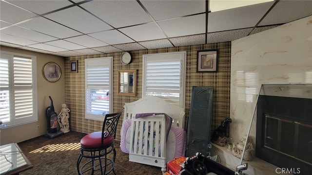 bedroom featuring multiple windows, dark colored carpet, and a drop ceiling