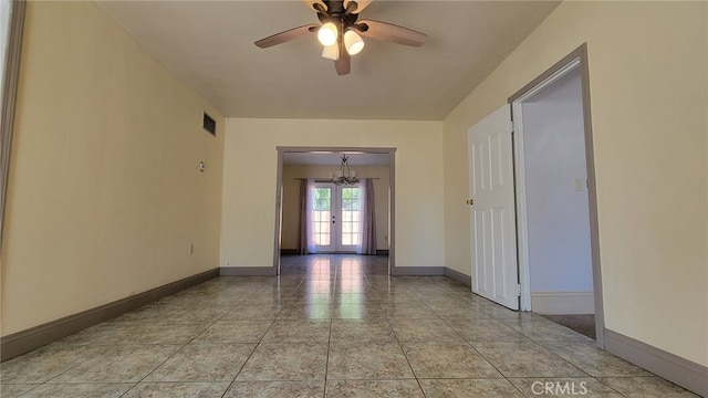 empty room with french doors, ceiling fan with notable chandelier, and light tile patterned flooring