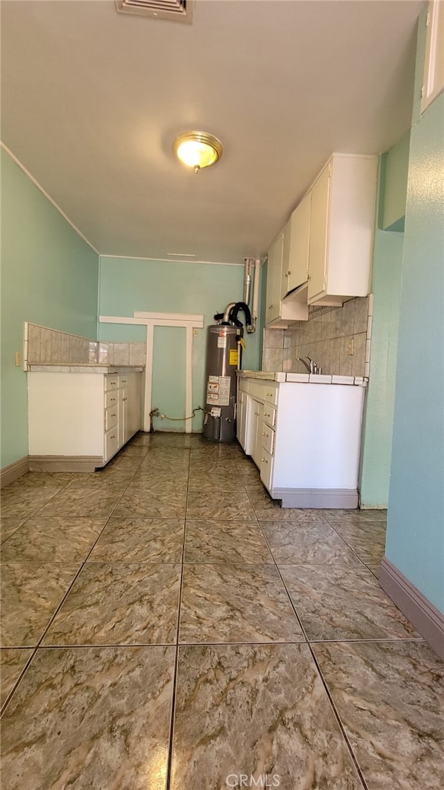 kitchen featuring decorative backsplash, water heater, and white cabinets