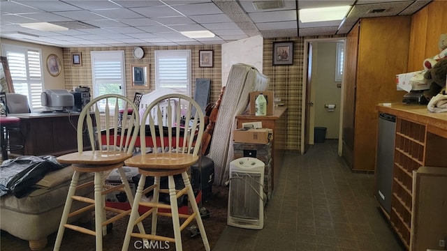 dining area with wood walls and a drop ceiling