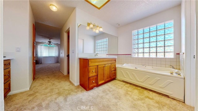 bathroom with a tub, ceiling fan, vanity, and a textured ceiling