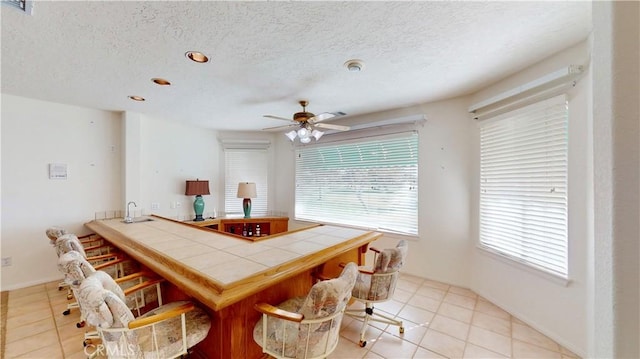 dining area with ceiling fan, light tile patterned flooring, and a textured ceiling