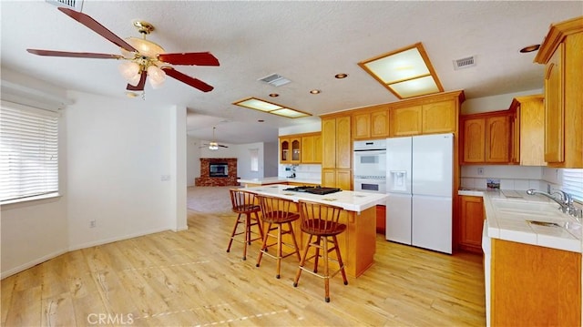 kitchen with a kitchen bar, a center island, white appliances, and light hardwood / wood-style flooring