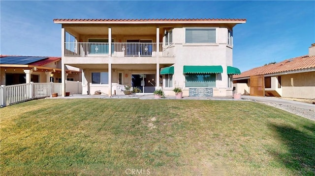 back of property with a lawn and a balcony