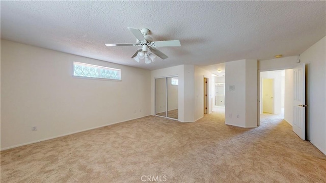 unfurnished bedroom featuring ceiling fan, a closet, light carpet, and a textured ceiling