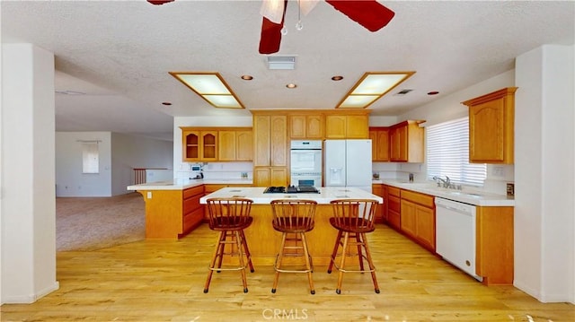 kitchen featuring a kitchen breakfast bar, a center island, white appliances, and light hardwood / wood-style flooring