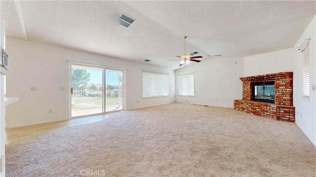 unfurnished living room featuring ceiling fan, light colored carpet, a fireplace, and vaulted ceiling