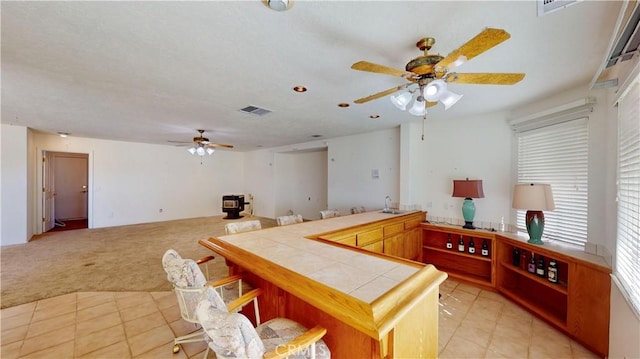 kitchen featuring tile countertops, a breakfast bar, light carpet, sink, and kitchen peninsula