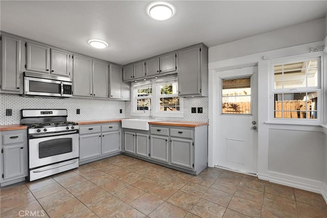 kitchen featuring wooden counters, appliances with stainless steel finishes, tasteful backsplash, and gray cabinetry