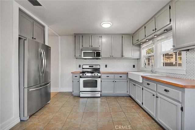 kitchen featuring gray cabinets, decorative backsplash, and appliances with stainless steel finishes