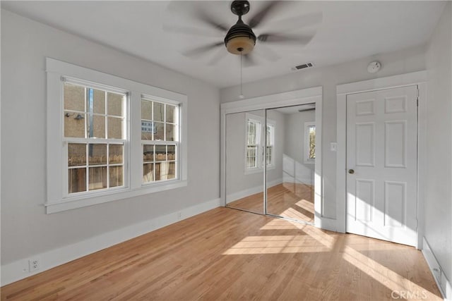 unfurnished bedroom featuring hardwood / wood-style floors, ceiling fan, and a closet