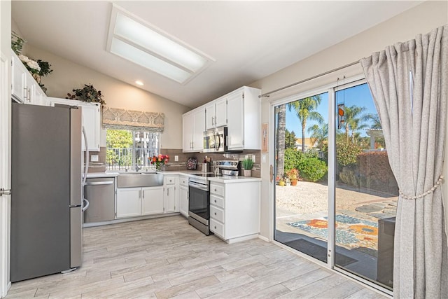 kitchen featuring white cabinets, stainless steel appliances, lofted ceiling, and sink