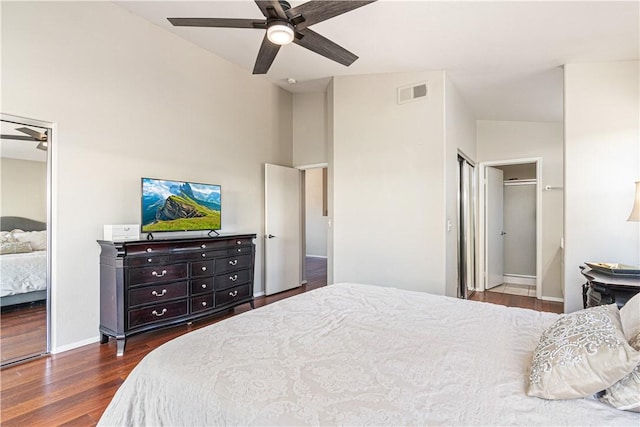 bedroom with ensuite bathroom, ceiling fan, dark wood-type flooring, and lofted ceiling