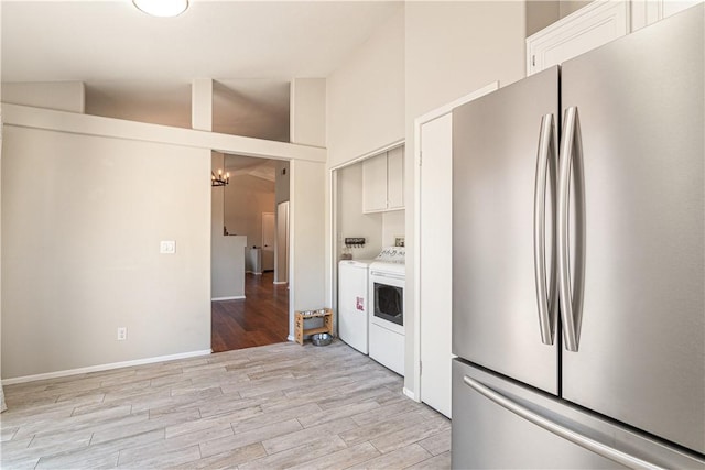 kitchen featuring separate washer and dryer, high vaulted ceiling, white cabinets, light hardwood / wood-style floors, and stainless steel refrigerator