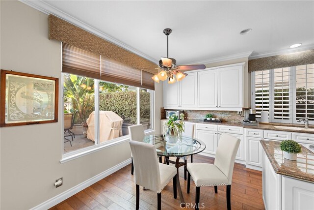 dining room featuring light wood-type flooring, ceiling fan, ornamental molding, and sink