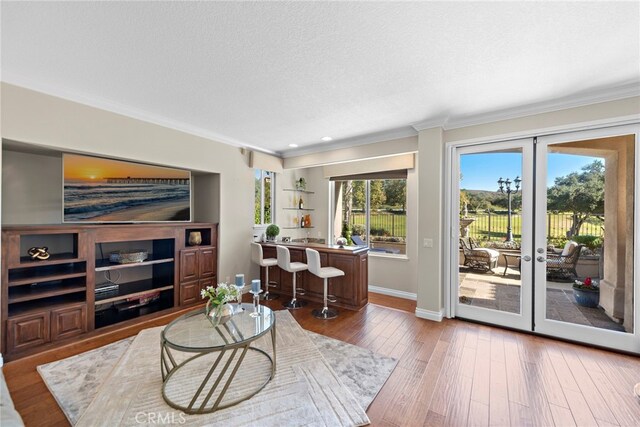 living room with wood-type flooring, french doors, plenty of natural light, and crown molding