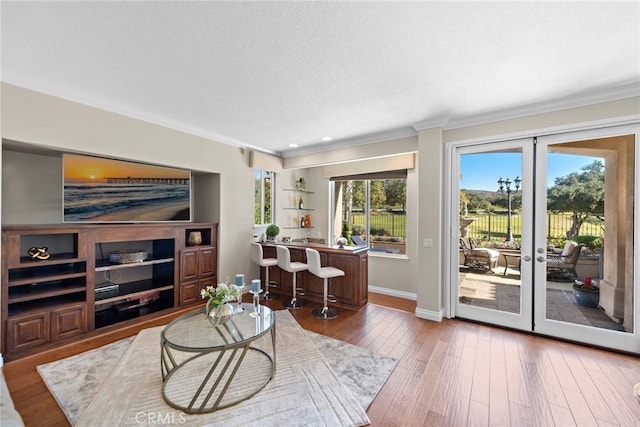 living room with french doors, crown molding, hardwood / wood-style floors, a textured ceiling, and baseboards