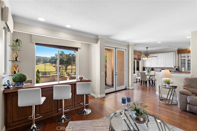 living room with hardwood / wood-style floors, ceiling fan, ornamental molding, and a textured ceiling