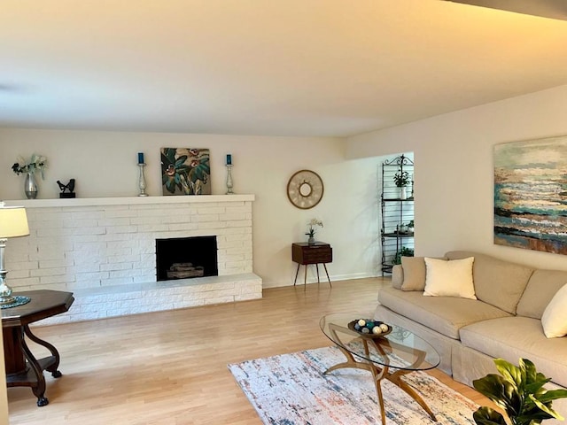 living room with a brick fireplace and hardwood / wood-style flooring