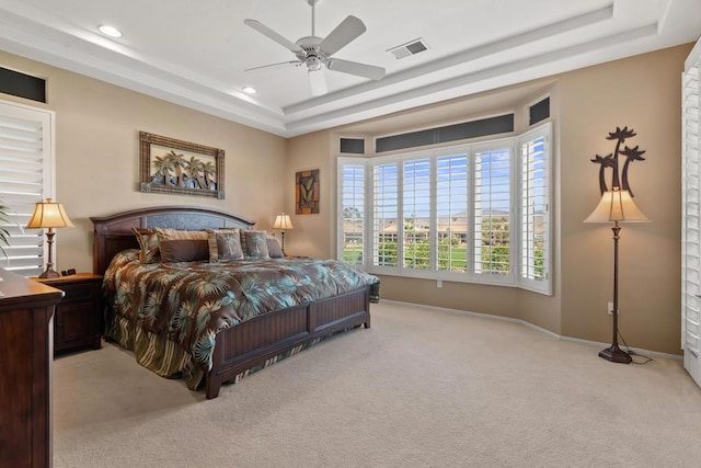 carpeted bedroom with a tray ceiling and ceiling fan