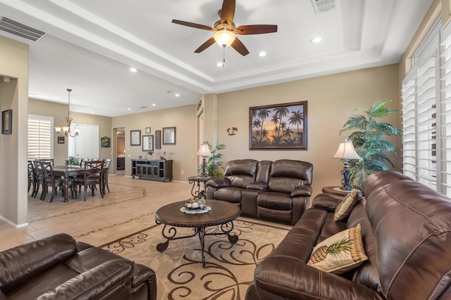 living room featuring ceiling fan with notable chandelier and a raised ceiling