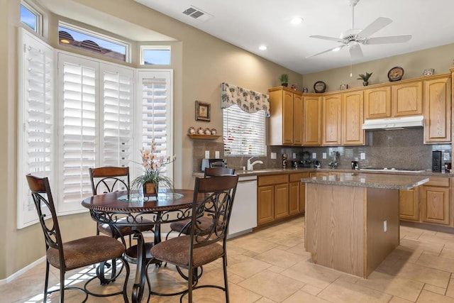 kitchen featuring sink, a center island, white dishwasher, ceiling fan, and decorative backsplash