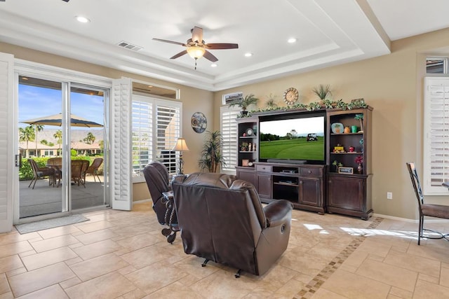 tiled living room with ceiling fan and a raised ceiling