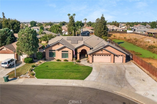 view of front of property with a garage, a front yard, and solar panels