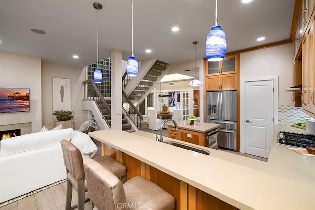 kitchen featuring sink, crown molding, decorative light fixtures, appliances with stainless steel finishes, and light wood-type flooring