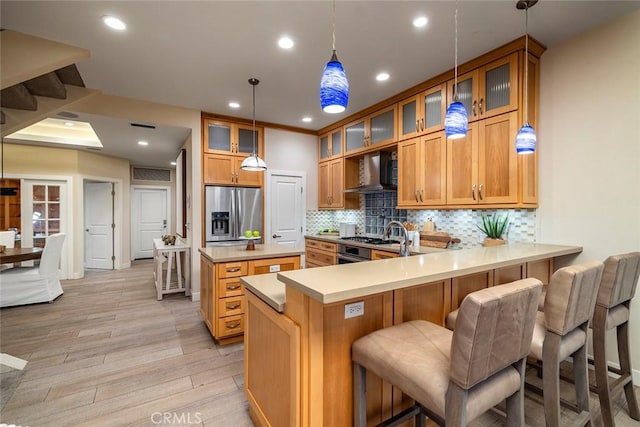 kitchen with kitchen peninsula, stainless steel fridge, backsplash, light hardwood / wood-style flooring, and a breakfast bar area