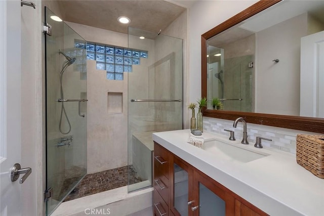 bathroom with vanity, tasteful backsplash, and a shower with door