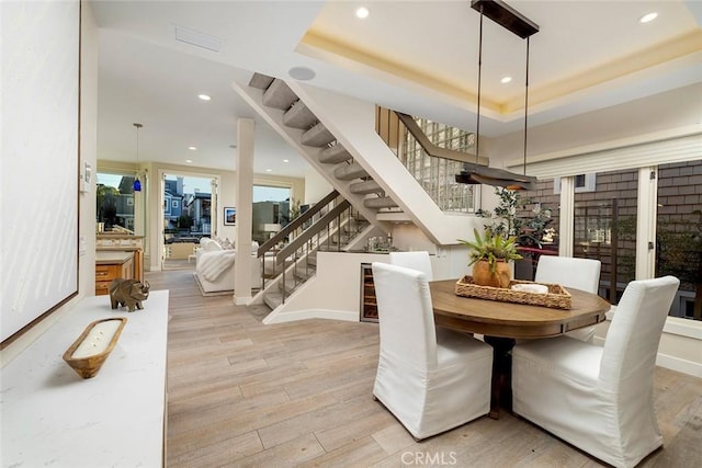 dining area with a tray ceiling, light hardwood / wood-style flooring, and plenty of natural light